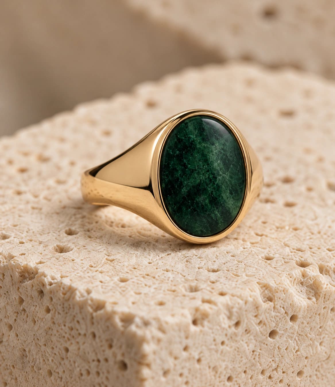 Green gemstone ring on textured stone
