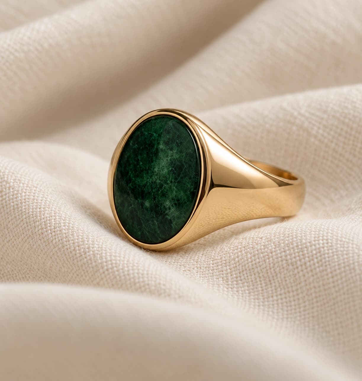 Green gemstone ring on a pale stone plinth